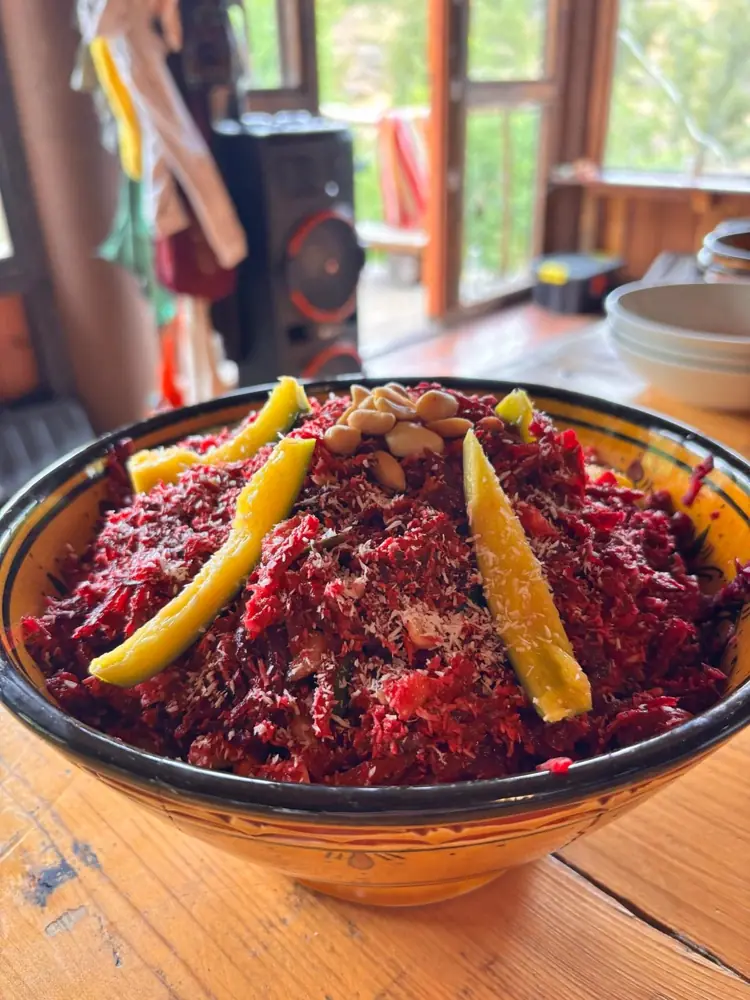 A bowl of beetroot salad topped with nuts and mango